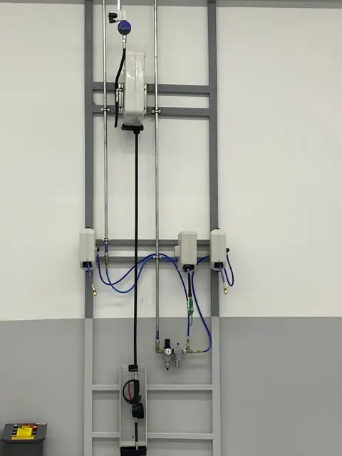 An einer Wandplatte montierte Druckluftleitung und Schlauchaufroller