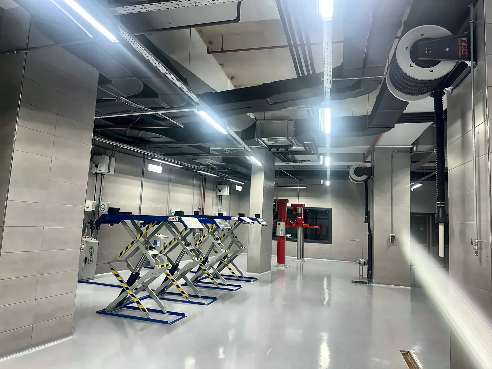 Row of scissor lifts and ceiling-mounted exhaust hose reels