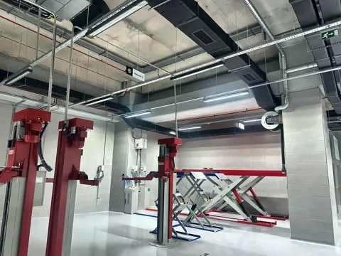 Schlauchaufroller der Abgasabsaugung in einer Werkstatt mit Scherenhebebühnen