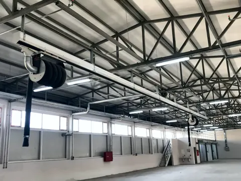 Abgasschiene und Aufroller in einer Stahlhalle